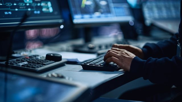 Close Up of a Professional Office Specialist Working on Desktop Computer in Modern Technological Monitoring Control Room with Digital Screens. Manager Typing on keyboard and Using Mouse.
